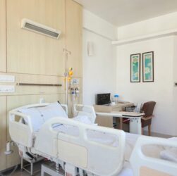 A hospital room with two empty beds and medical equipment visible