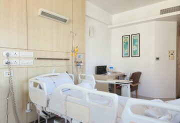 A hospital room with two empty beds and medical equipment visible