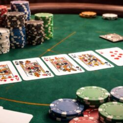 A close-up view of a poker game with a variety of chips and playing cards on a green felt table.