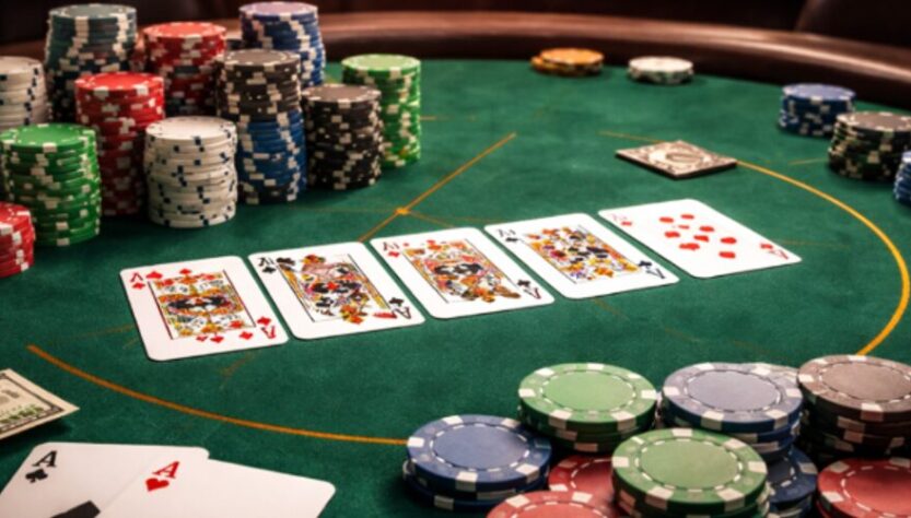 A close-up view of a poker game with a variety of chips and playing cards on a green felt table.